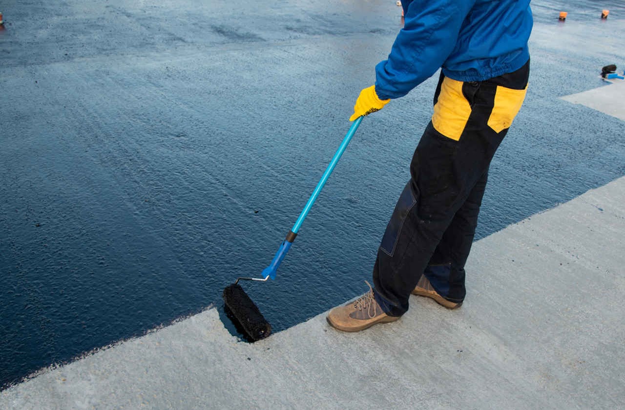Waterproof coating being rolled onto a roof